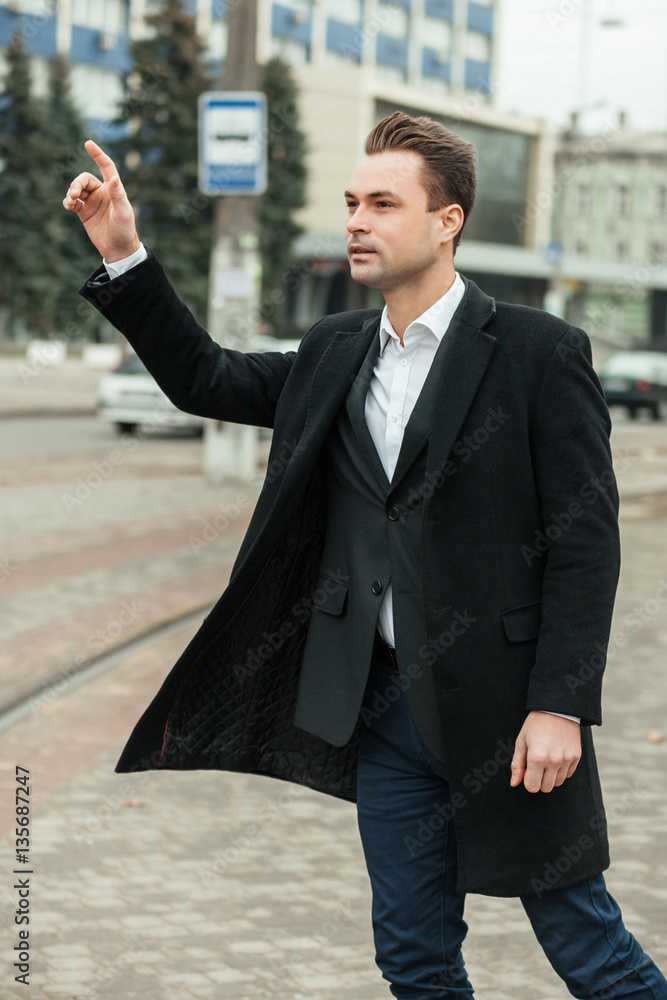 The solid man walks and catches a taxi. On him a black classical coat, a jacket and a white shirt. He very gracefully looks. The solid man walks and catches a taxi. On him a black classical coat, a jacket and a white shirt. He very gracefully looks.