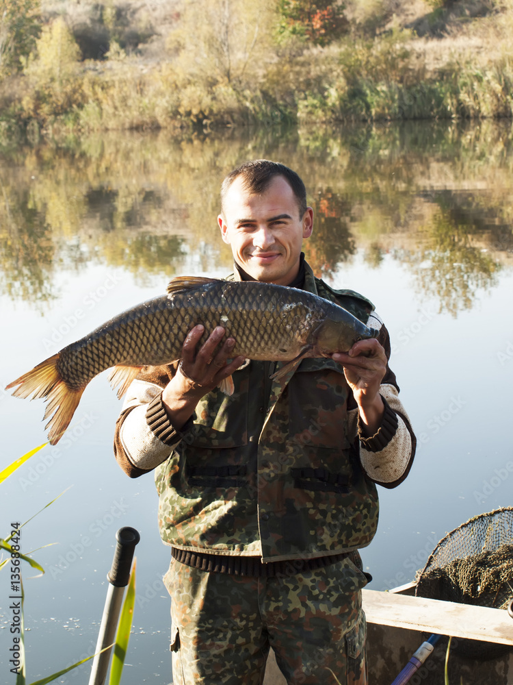 Fisherman With fish Mirror Carp. Fishing on river on autumn Fisherman With fish Mirror Carp. Fishing on river on autumn