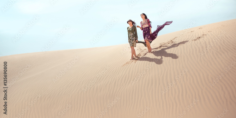 Fototapeta premium Travel concept. Two gordeous women sisters traveling in desert.