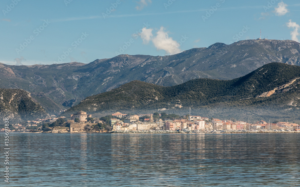 View across St Florent bay in Corsica to the town of Saint Florent with mountains behind
