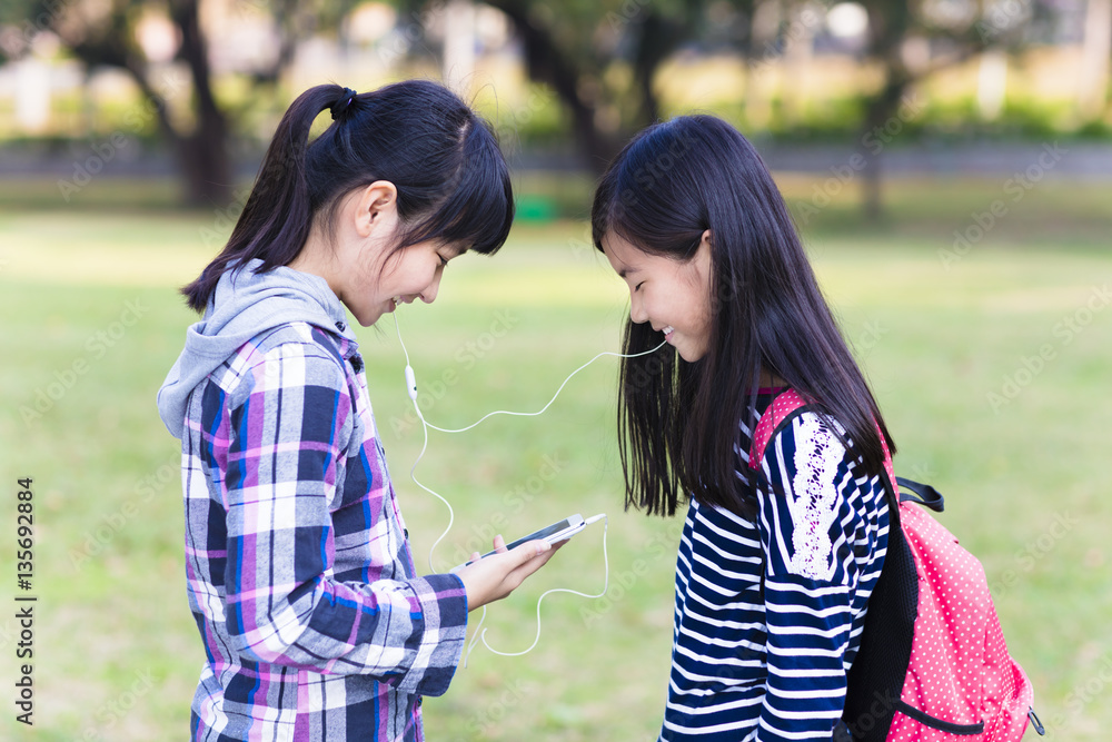 Two teenage girls friends watching the smart phone in school Two teenage girls friends watching the smart phone in school