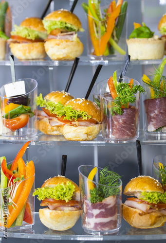 Mini desserts and meat canapes vegetable snacks in plastic cups canapes