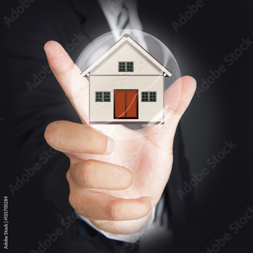 Businessman hand holding bubble with little house