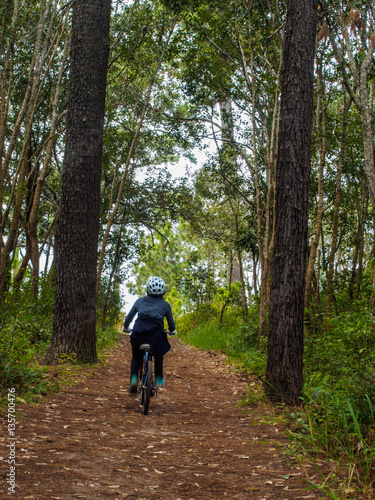 Woman cycling in a pine forest