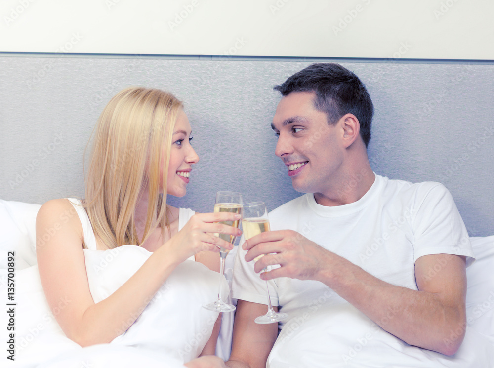 smiling couple with champagne glasses in bed smiling couple with champagne glasses in bed