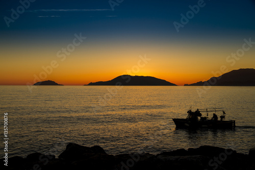 sole al tramonto sul mare nel Golfo dei poeti con barca da pesca