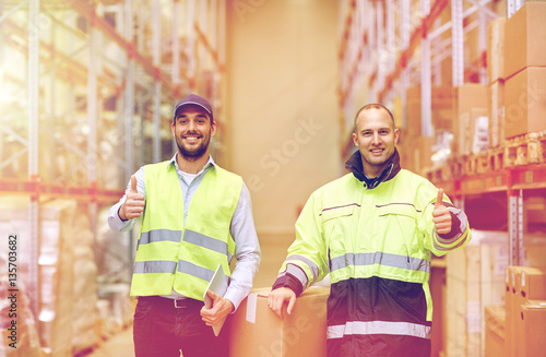 men with boxes showing thumbs up at warehouse