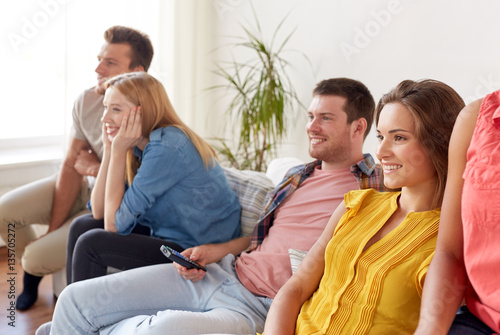 happy friends with remote watching tv at home