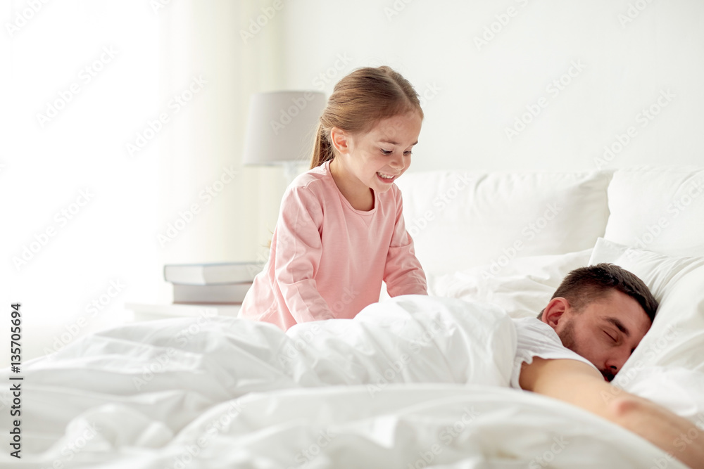 little girl waking her sleeping father up in bed little girl waking her sleeping father up in bed