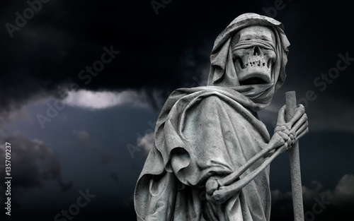 The Grim Reaper Death personified statue wanders in the dark night