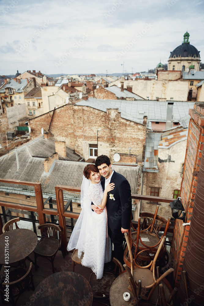 Groom & bride standing on the roof with a great cityscape