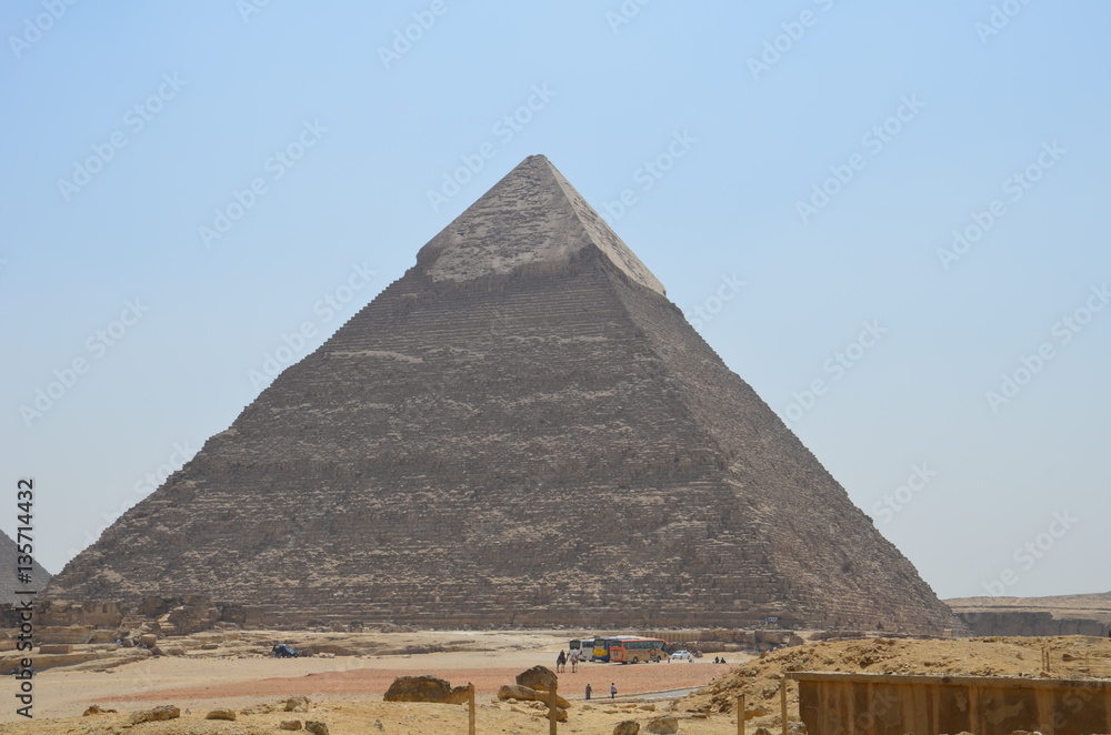 Pyramid in sand dust under gray clouds