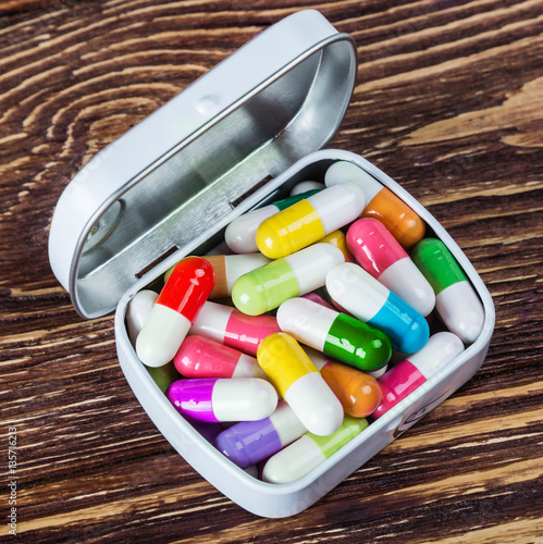 box with different color pills on a wooden table photo