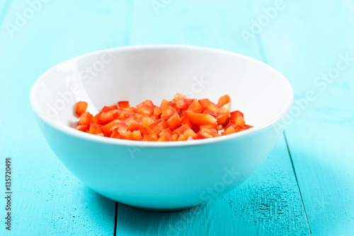 Chopped Red Capsicum In White Bowl On Turquoise Table