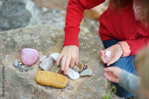 Bild auf Leinwand Two cute little sisters collecting beautiful stones on a pebble beach