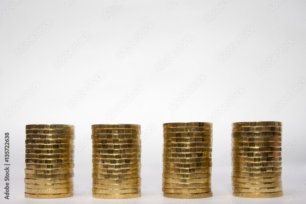 Four identical height of the stack of coins on a light background, the top place for an inscription Four identical height of the stack of coins on a light background, the top place for an inscription