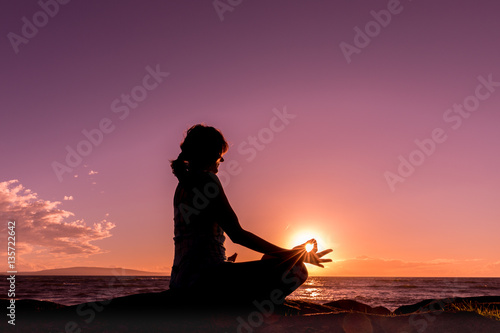 Woman Silhouetted Practicing Yoga on the Beach at Sunset
