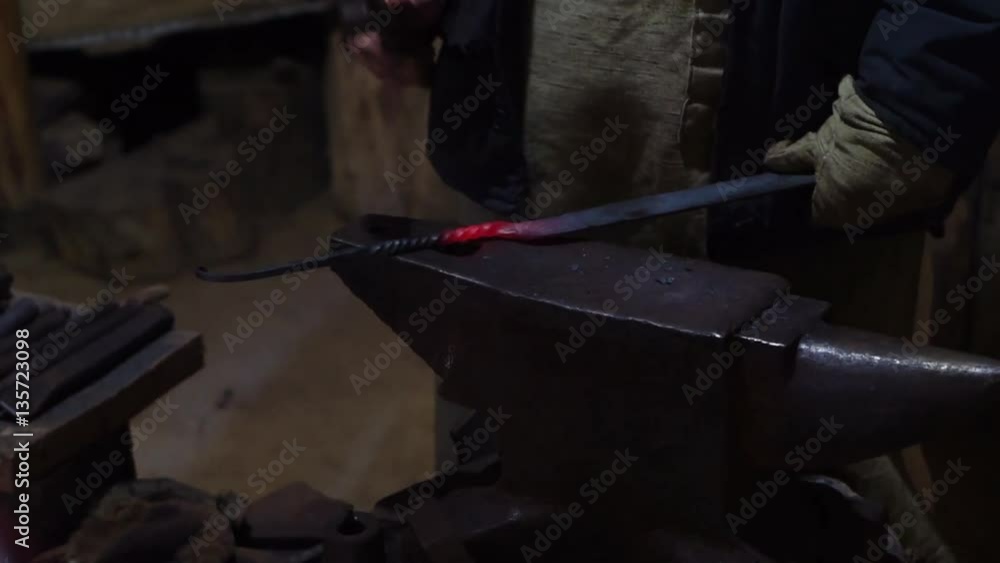 Blacksmith forging dipping hot metal from furnace and creates tools, furniture. beats a piece of hot metal with a hammer on an anvil. Close up shot in low light Blacksmith forging dipping hot metal from furnace and creates tools, furniture. beats a piece of hot metal with a hammer on an anvil. Close up shot in low light