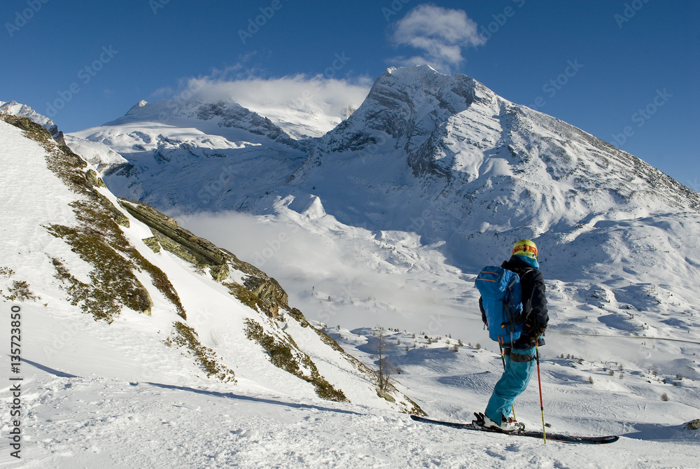 landscape of the Swiss Alps covered by snow and skier who practice ski mountaineering looking mountains and the horizon, on a sunny day, Switzerland, Simplon Pass, Mount Breithorn