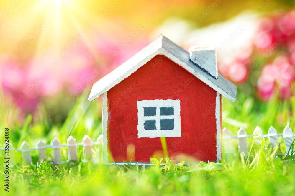red wooden house model on the grass in garden red wooden house model on the grass in garden