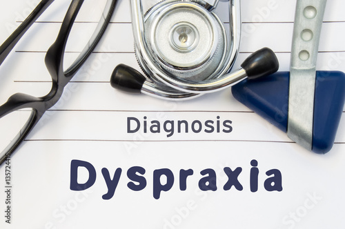 Neurological diagnosis of Dyspraxia. Neurological hammer, stethoscope and doctor's glasses lie on doctor workplace on sheet of notebook, labeled with the title of medical diagnosis of Dyspraxia photo