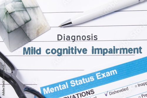 Psychiatric Diagnosis Mild Cognitive Impairment. Medical book or form with the name of diagnosis Mild Cognitive Impairment is on table of doctor surrounded by questionnaire to determine mental state photo