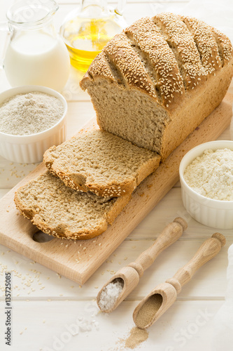 Ingredients for homemade wheat and rye bread with sesame seeds on white wooden table. Selective focus