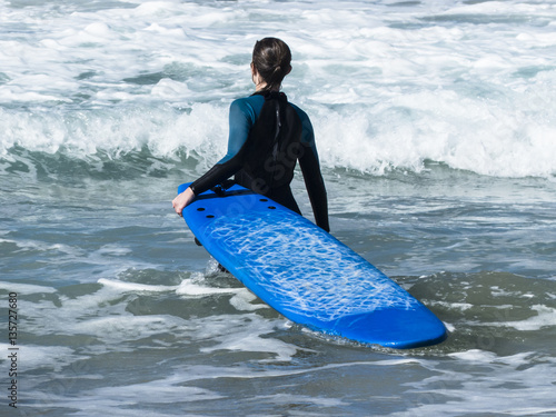 Surfer with surf board trying to get out trough the surf to catc photo