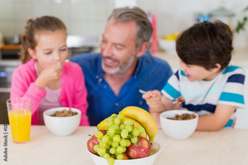 Smiling father and kids having breakfast in kitchen Smiling father and kids having breakfast in kitchen