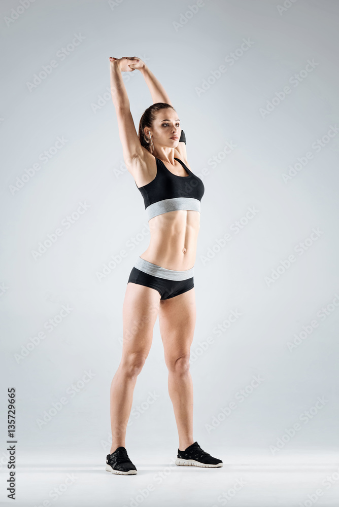 Athletic girl stretching on a grey background Athletic girl stretching on a grey background