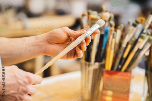 artist is holding the brush. Paint Brushes on a blur background