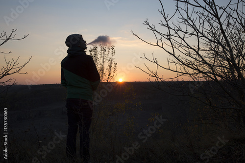 The young beautiful boy vaper against the sunset