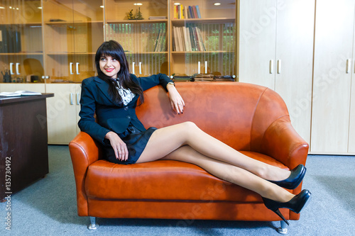 Young beautiful businesswoman resting lying on a sofa in office photo