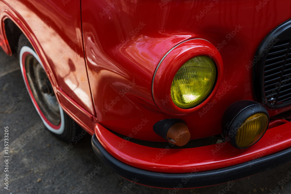 Close-up view of red sports car headlight.