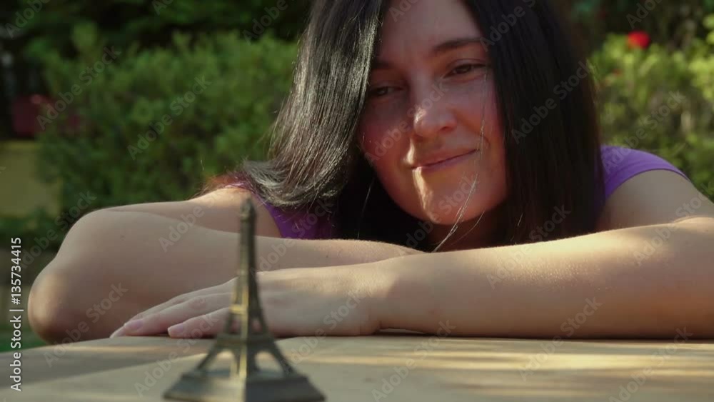 Woman looks at a model of the Eiffel Tower in sunny summer day Woman looks at a model of the Eiffel Tower in sunny summer day