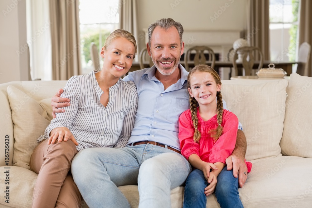 Portrait of smiling parents and daughter sitting 