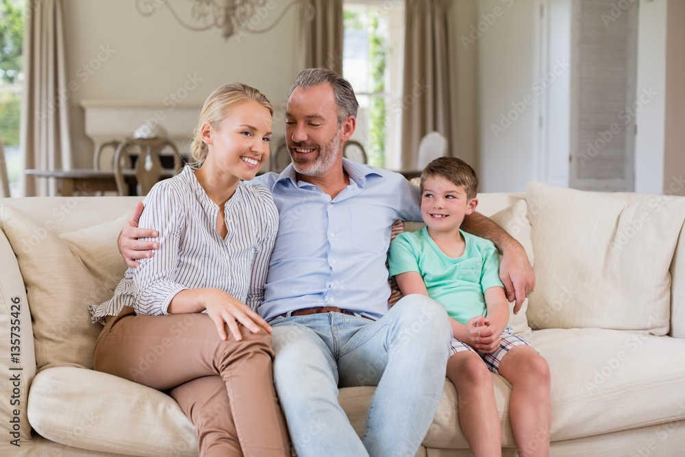 Smiling parents and son sitting on sofa in living room Smiling parents and son sitting on sofa in living room