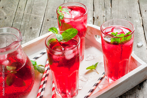 Summer iced drink - tea or juice with ice and mint. On rustic wooden table, with white tray, copy space photo