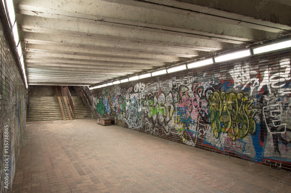 Abandoned underground walk-through with graffiti wall at night.   