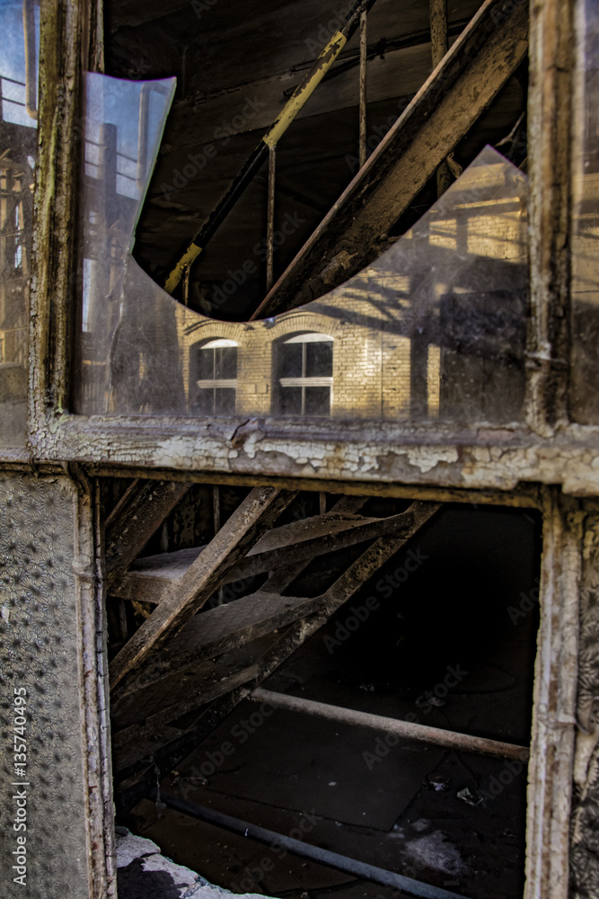 Stairs behind the broken window of an old factory