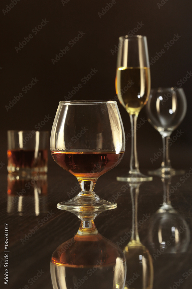 Glasses with white, red wine and cognac or whisky on mirror table. Celebrities composition.