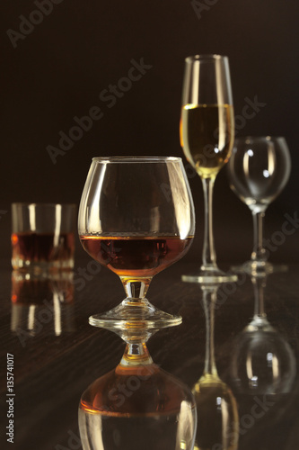 Glasses with white  red wine and cognac or whisky on mirror table. Celebrities composition.
