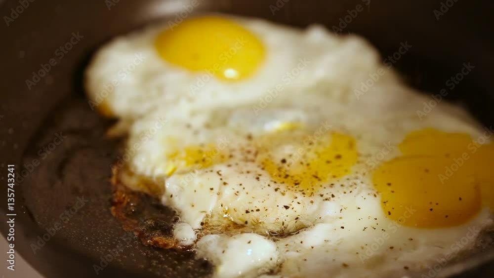 Close up shot of cooking fried eggs with spice in frying pan for breakfast Close up shot of cooking fried eggs with spice in frying pan for breakfast