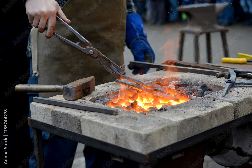 The smith keeps nippers a metal detail in a forge brazier The smith keeps nippers a metal detail in a forge brazier