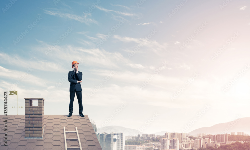 Engineer man standing on roof and looking away. Mixed media