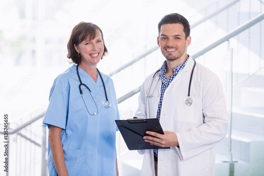 Nurse and doctor discussing over clipboard in corridor Nurse and doctor discussing over clipboard in corridor