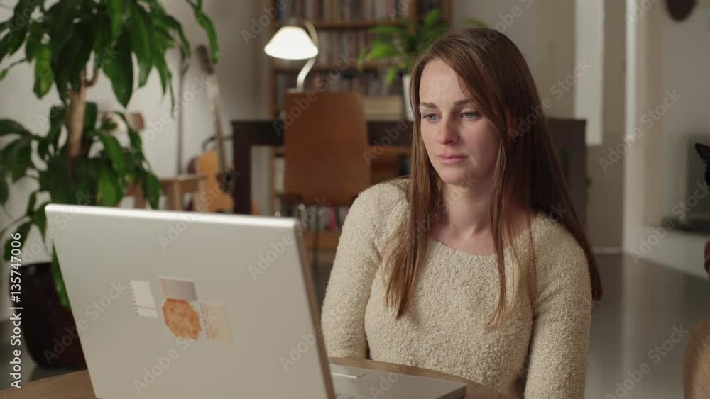 Young woman watches videos on internet in her laptop at home. She watches very concentrated and serious with a suddenly look of disgust. Dolly shot to the right. Young woman watches videos on internet in her laptop at home. She watches very concentrated and serious with a suddenly look of disgust. Dolly shot to the right.