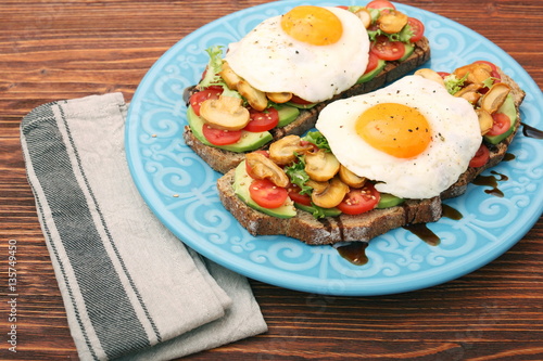 Sandwich with egg, tomato, greens, and mushrooms