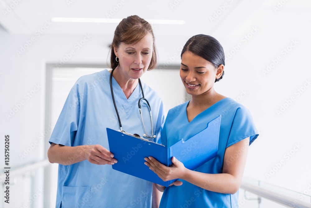 Nurse and doctor discussing over clipboard Nurse and doctor discussing over clipboard