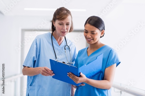 Nurse and doctor discussing over clipboard photo